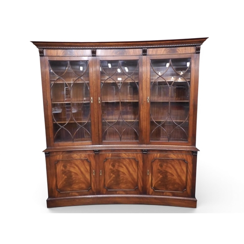 3 - A 20th century mahogany veneered concave library bookcase with moulded dentil cornice over three bea... 