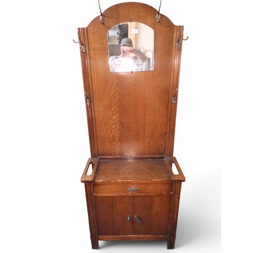 39 - An early 20th century oak veneered mirror backed hall stand with single drawer over pair of cabinet ... 