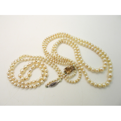 755 - A double string of pearls with a yellow metal flower clasp, and a further single string of pearls wi... 