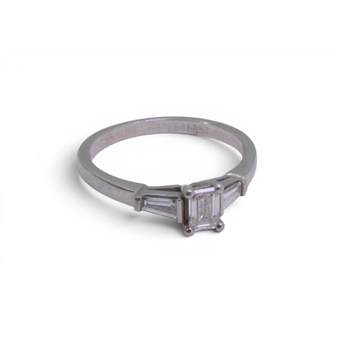 707 - A platinum and diamond three stone ring set with a GIA inscribed emerald cut diamond of estimated ap... 