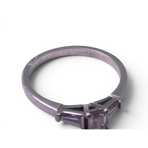 707 - A platinum and diamond three stone ring set with a GIA inscribed emerald cut diamond of estimated ap... 