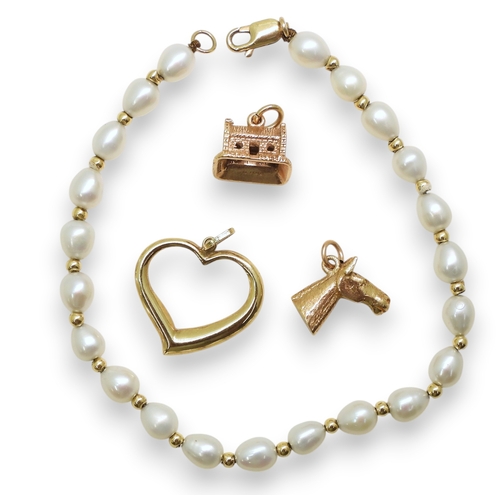736 - A 9ct gold horse's head charm and a further example in the shape of a croft, a heart shaped pendant ... 