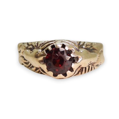 743 - A yellow metal ring set with a garnet with a stag to each shoulder, the antlers make up the claws of... 