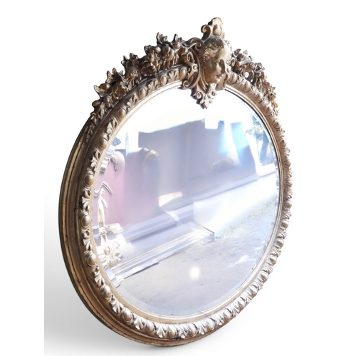 36 - An impressively large 19th century oval framed wall mirror with moulded frame surmounted with ladies... 