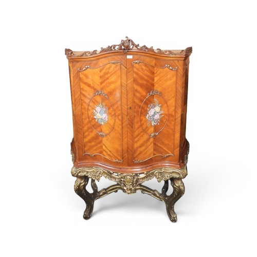 53 - A large continental style serpentine front drinks cabinet with scrolled foliate surmount over pair o... 
