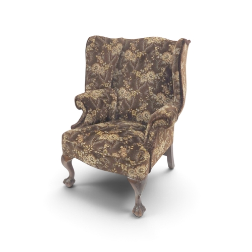 2019 - AN EARLY 20TH CENTURY BROWN FLORAL UPHOLSTERED WINGBACK ARMCHAIR&nbsp;with rolled arms on serpentine... 