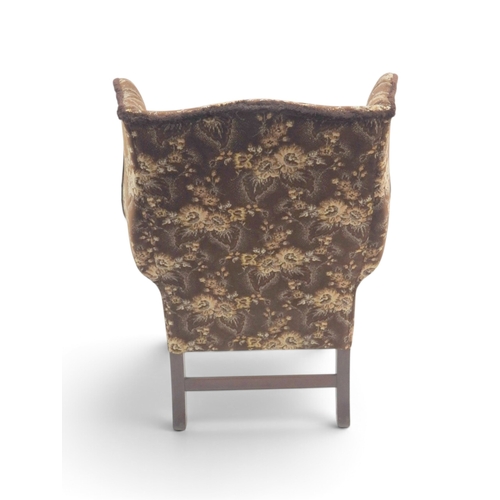 2019 - AN EARLY 20TH CENTURY BROWN FLORAL UPHOLSTERED WINGBACK ARMCHAIR&nbsp;with rolled arms on serpentine... 