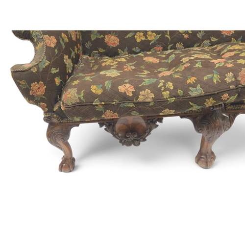 2021 - A 19TH CENTURY CONTINENTAL FLORAL UPHOLSTERED HUMPED WINGBACK SETTEEwith rolled arms on three carved... 