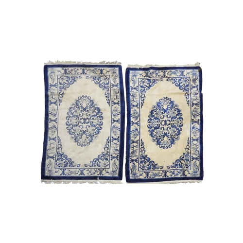 24 - A pair of cream ground deep pile Oriental style rugs with blue scrolled floral/foliate decorated cen... 