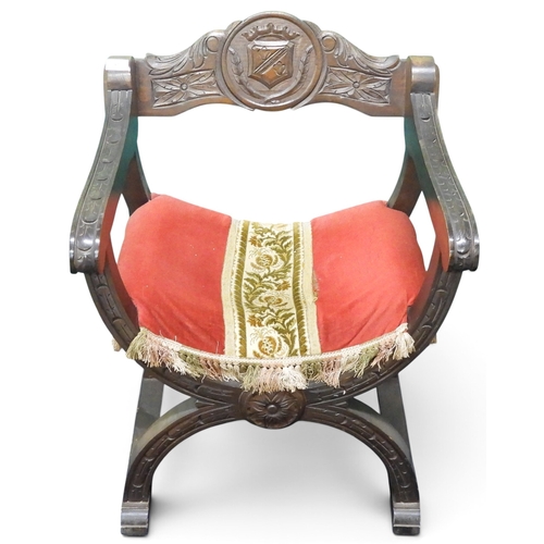 37 - A 20th century cross framed Dagobert style armchair with armorial crest carved into backrest over up... 