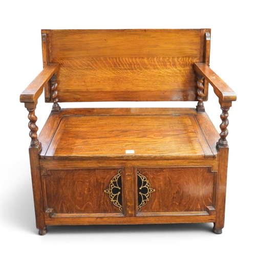 50 - A 20th century oak monks bench with rectangular back/top over shaped arms with barley twist uprights... 