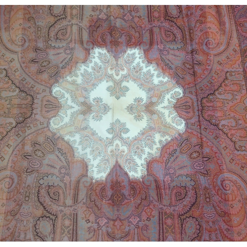 8040 - A long Paisley shawl woven in polychrome wools, the central cream cartouche with palmettes and sprig... 