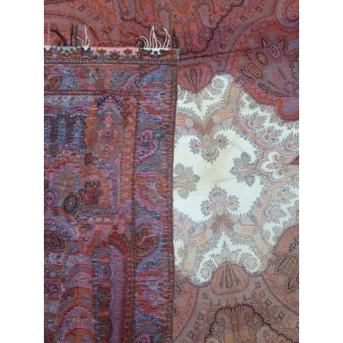 8040 - A long Paisley shawl woven in polychrome wools, the central cream cartouche with palmettes and sprig... 