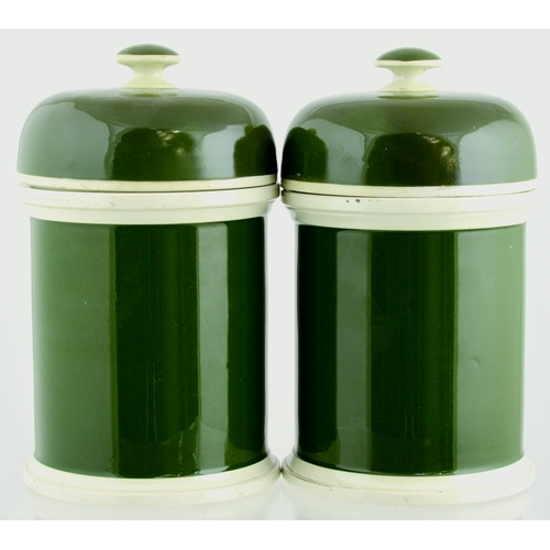 667 - PHARMACY LABEL UNDER GLASS JAR DUO. 8.5ins tall. Cylindrical form with domed lids, green glaze edged... 