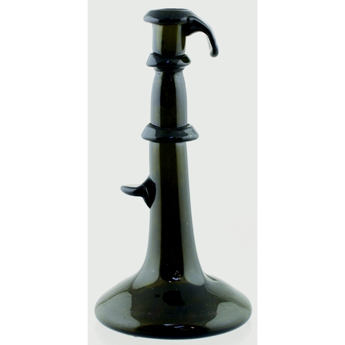 696 - ENGLISH HOGSCRAPER BOTTLE/ CANDLESTICK. 6.75ins tall. Dark green, almost black glass bottle formed a... 