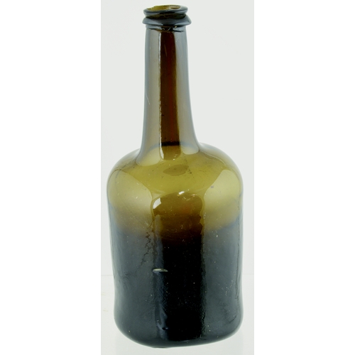 704 - FAT BODIED CYLINDER WINE BOTTLE. 9.75ins tall. Variating amber/ brown, slighlty dimpled glass, long ... 