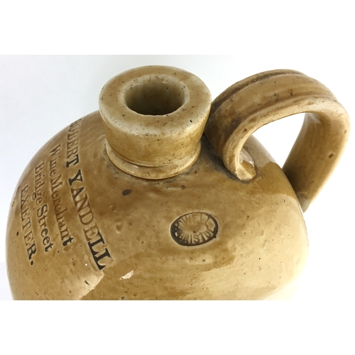 595 - EXETER SPIRIT FLASK. 11ins tall. T.t. tan/ flat sided flagon, rounded shoulders, rear handle. Front ... 