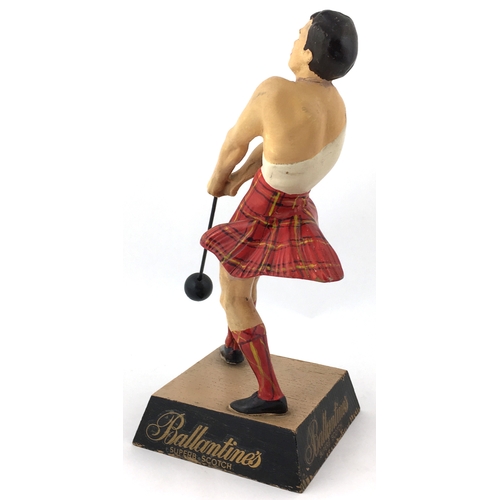 142 - BALLANTINES BACK BAR FIGURE. 9.75ins tall. Rubberoid figure of kilted shot putter stood on wooden pl... 