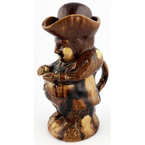 87 - ROCKINGHAM TREACLE GLAZED POTTERY SNUFF TAKER. 10ins tall. Full figural of portly period clad gent s... 