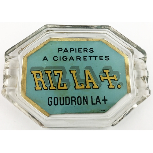 165 - RIZLA GLASS ASHTRAY. 5.25 by 3.75ins diam. Octagonal glass with green, gold and black paper print to... 