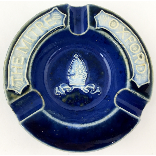 209 - OXFORD THE MITRE ASHTRAY.  4.5 ins diam. Deep blue stoneware with raised crown to  centre, letters t... 