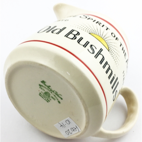 195 - OLD BUSHMILLS WATER JUG. 4ins tall. Red line below lip, black & yellow side design featuring rising ... 