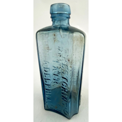 42 - HAIR RESTORER BOTTLE. 5.75ins tall. Ice blue glass, rectangular form, rounded shoulders & chamfered ... 