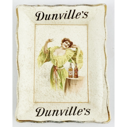 149 - DUNVILLES WHISKY ASHTRAY. 4.8 x 3.7ins. Shapely lady about to imbibe in one of two different bottles... 