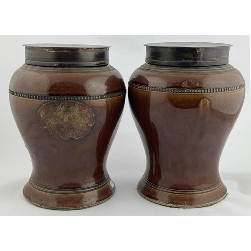 399 - PHARMACY JARS DUO. 9.5ins tall. Dark tan glaze, lidded top, one with paper label to both sides. Buch... 