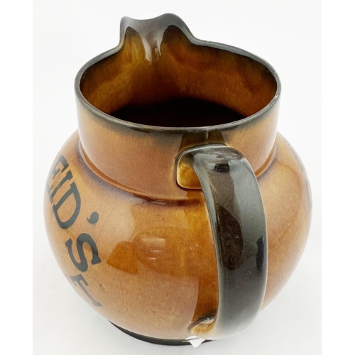 27 - REIDS STOUT WATER JUG. 4.8ins tall, pouring lip, rear handle. Varied brown shiny body glaze. Transfe... 