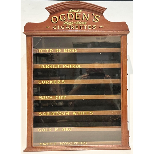 85 - OGDENS CIGARETTES DISPENSING CABINET. 31.5 x 22 x 5.25ins. Brown painted wood, shapely finial with g... 
