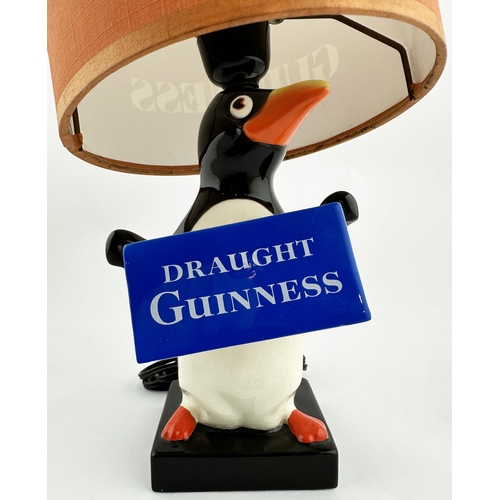 243 - 14.3ins to shade top. Coloured Carltonware penguin base holding promotional banner. Named shade (top... 