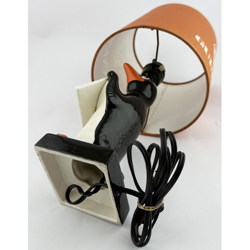 243 - 14.3ins to shade top. Coloured Carltonware penguin base holding promotional banner. Named shade (top... 