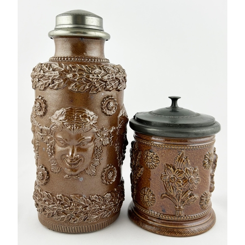 88 - SALT GLAZE TOBACCO JAR DUO. Tallest 9.5ins. One floral design other with added faces. Sligh nicks to... 