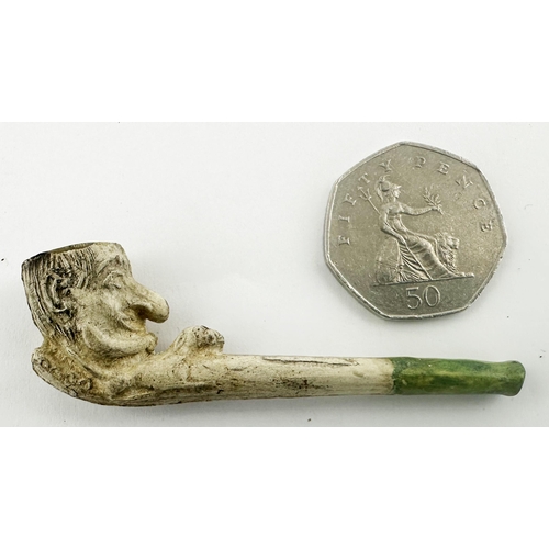 448 - MINIATURE PUNCH PIPE. 2.7ins long. Detailed Mr Punch like head as pipe bowl, green mouthpiece. Some ... 