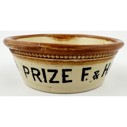 104 - F & H HORNBY FIRST PRIZE CREAM DISH. 1.5 x 4.25ins. Brown top, black transfer. Prize medals with dat... 