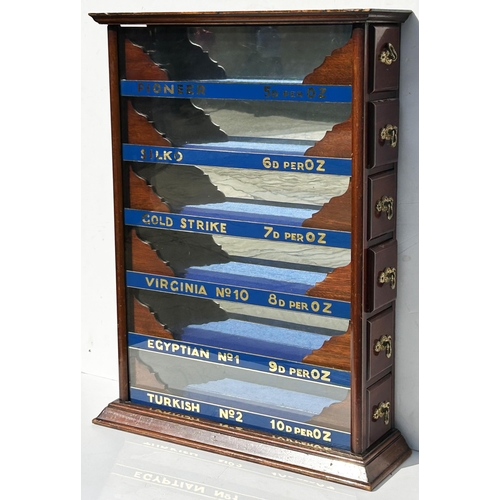 138 - CIGARETTE DISPLAY CABINET. 27 x 19.5 x 5.5ins. Dark wood with 6, sliding, elaborately shaped handled... 