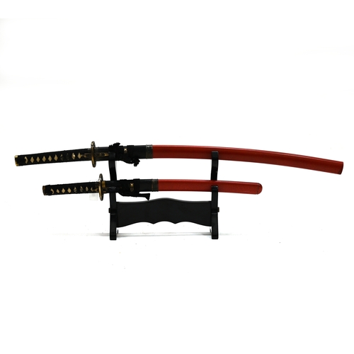 416 - A Japanese Katana, or Samurai sword, and a smaller Wakizashi, both with scabbards and mounted on a w... 