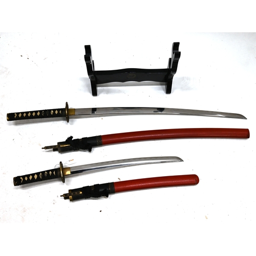 416 - A Japanese Katana, or Samurai sword, and a smaller Wakizashi, both with scabbards and mounted on a w... 