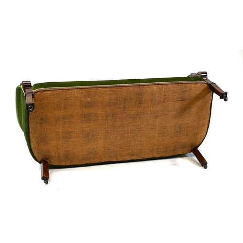 1013 - An early 20th Century green upholstered two seat sofa with sweeping Mahogany arms and feet. On caste... 