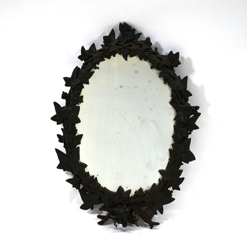 900 - An early 20th Century cast iron framed oval wall mirror. The frame profusely decorated in grapes and... 