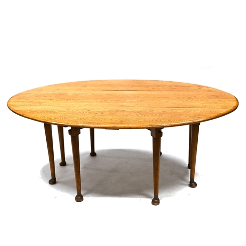 916 - A 20th Century reproduction of a Georgian style wake table in mid oak, supported on eight legs with ... 