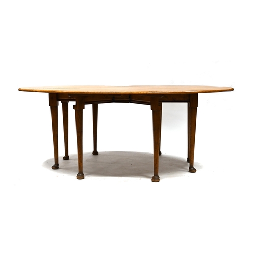 916 - A 20th Century reproduction of a Georgian style wake table in mid oak, supported on eight legs with ... 