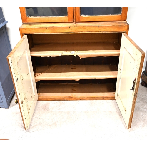 979 - A stripped Pine shallow depth cabinet with glazed shelving above and shelved cupboard below c1900. W... 