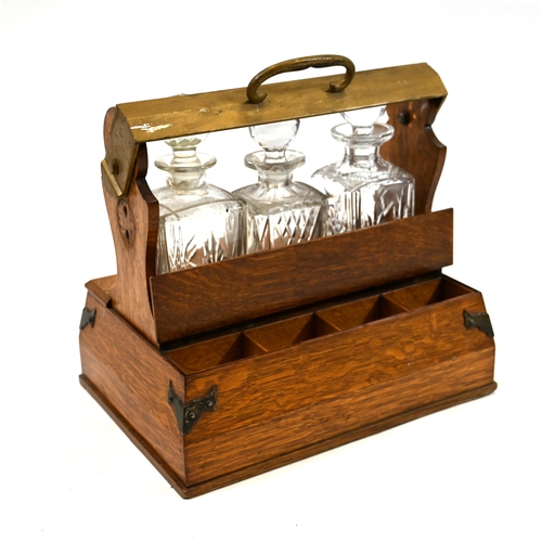 999 - An Edwardian oak tantalus with locking bar containing three square form decanters. The brass bound b... 