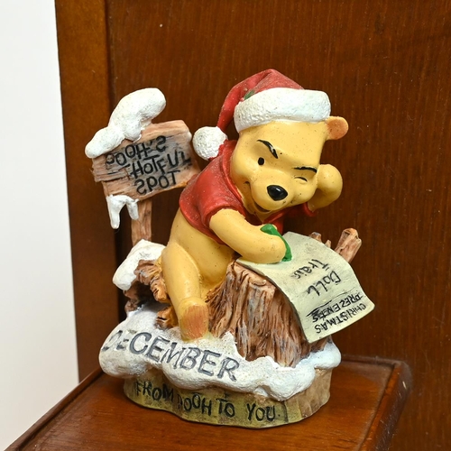 335 - A Danbury Mint Winnie The Pooh perpetual calendar, on a wooden display cabinet 