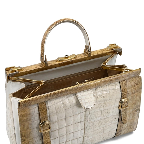 562 - A vintage cream and brown crocodile skin handbag, with a brass push lock and straps and having suede... 