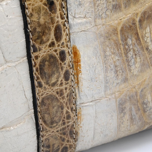 562 - A vintage cream and brown crocodile skin handbag, with a brass push lock and straps and having suede... 