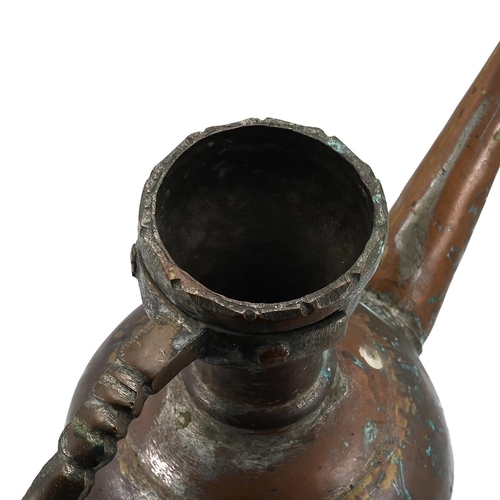 569 - A Middle Easter hammered copper water jug with pronounced brass handle and long angled spout. H 34.5... 