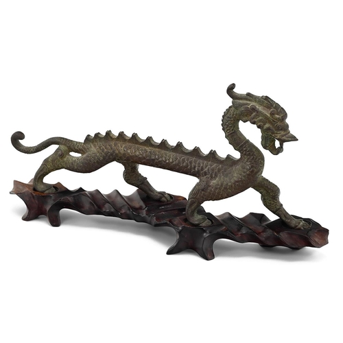 575 - A Chinese bronze model of a dragon, on a fitted hardwood stand, 30cm long, 14cm high 